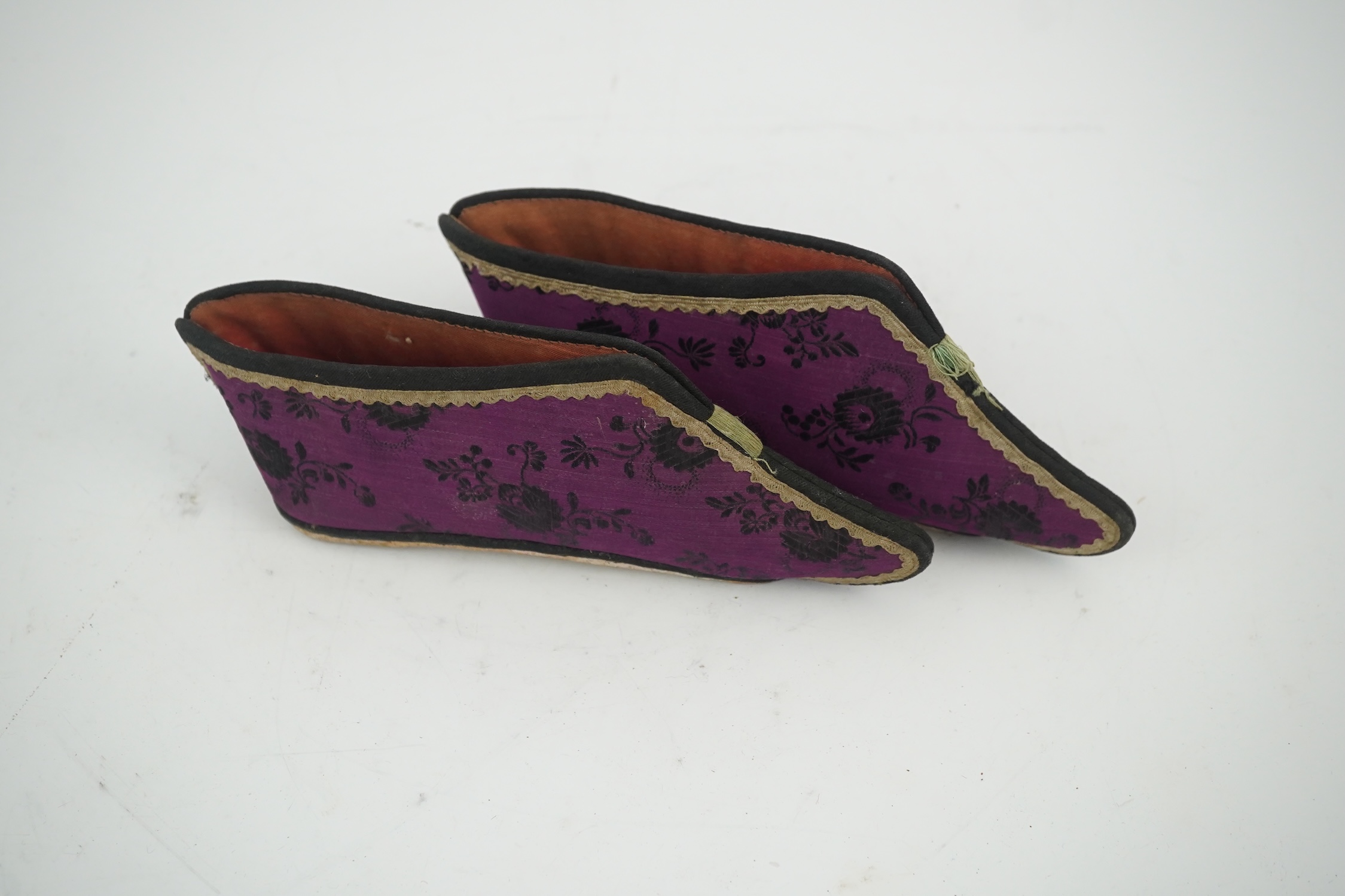 Four pairs of late 19th / early 20th Chinese ladies bound foot shoes, made in various coloured silks, with colourful floral embroidered motifs, two pairs with decorative silk pom-poms and another made of purple and black